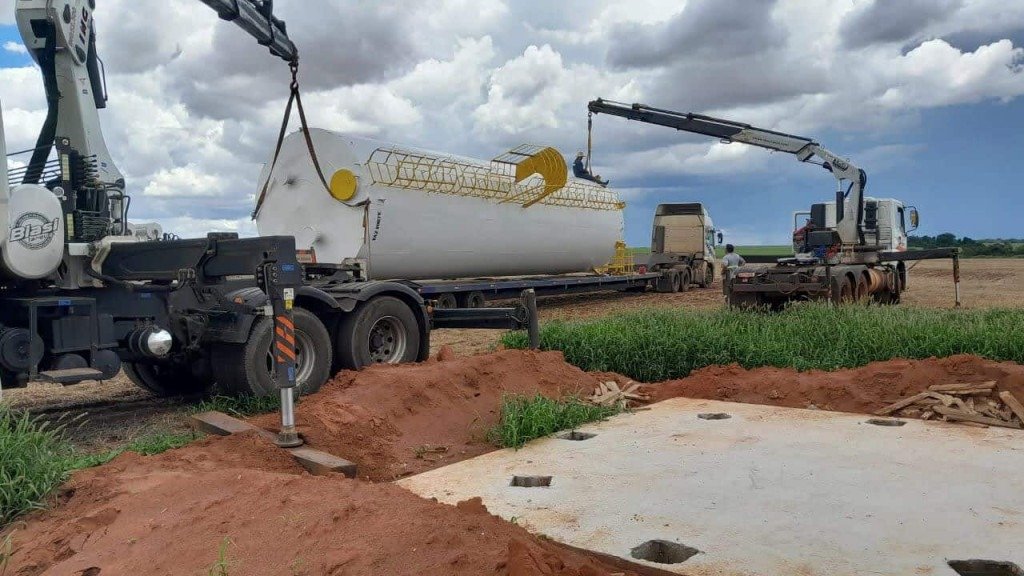 Caminhão colocando caixa d'água em base para caixa d'água com cabos