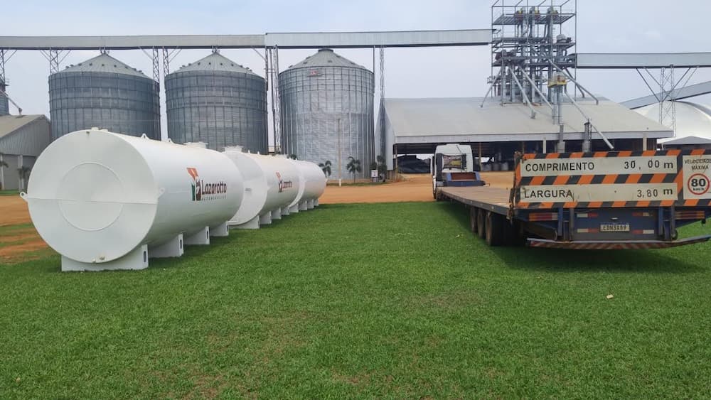 Reservatório de combustível com três tanques brancos e caminhão ao lado