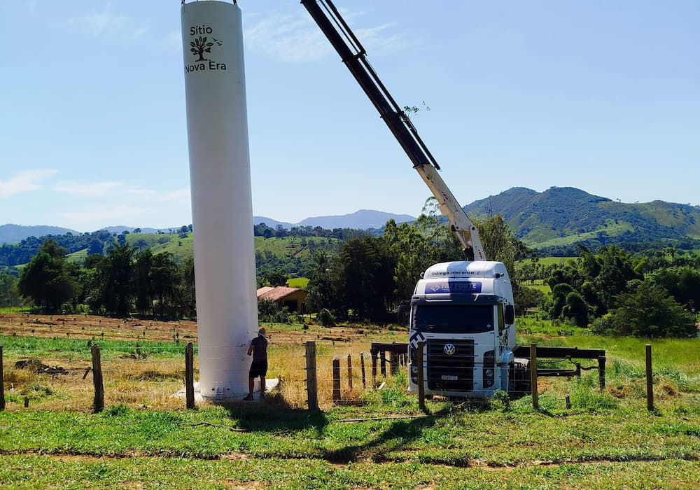 Caixa d'água de grande porte sendo instalada por caminhão com gancho